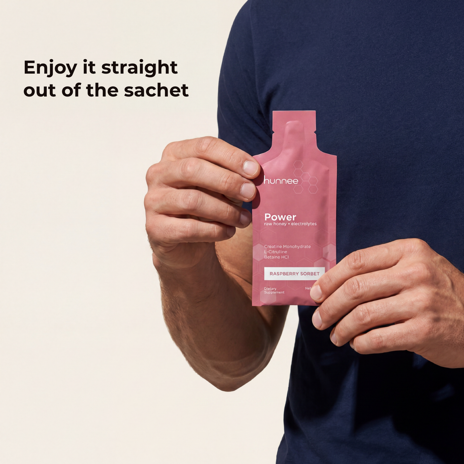 Person holding a pink 'hunnee' power sachet against a beige background