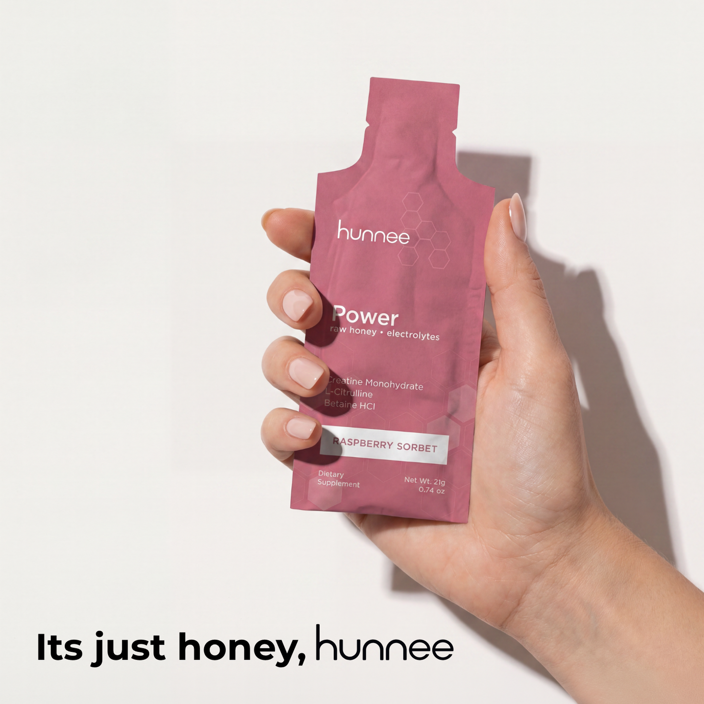 Hand holding a pink 'hunnee' package against a white background