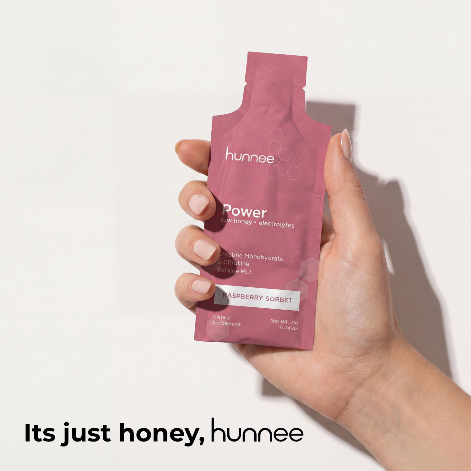 Hand holding a pink 'hunnee' package against a white background