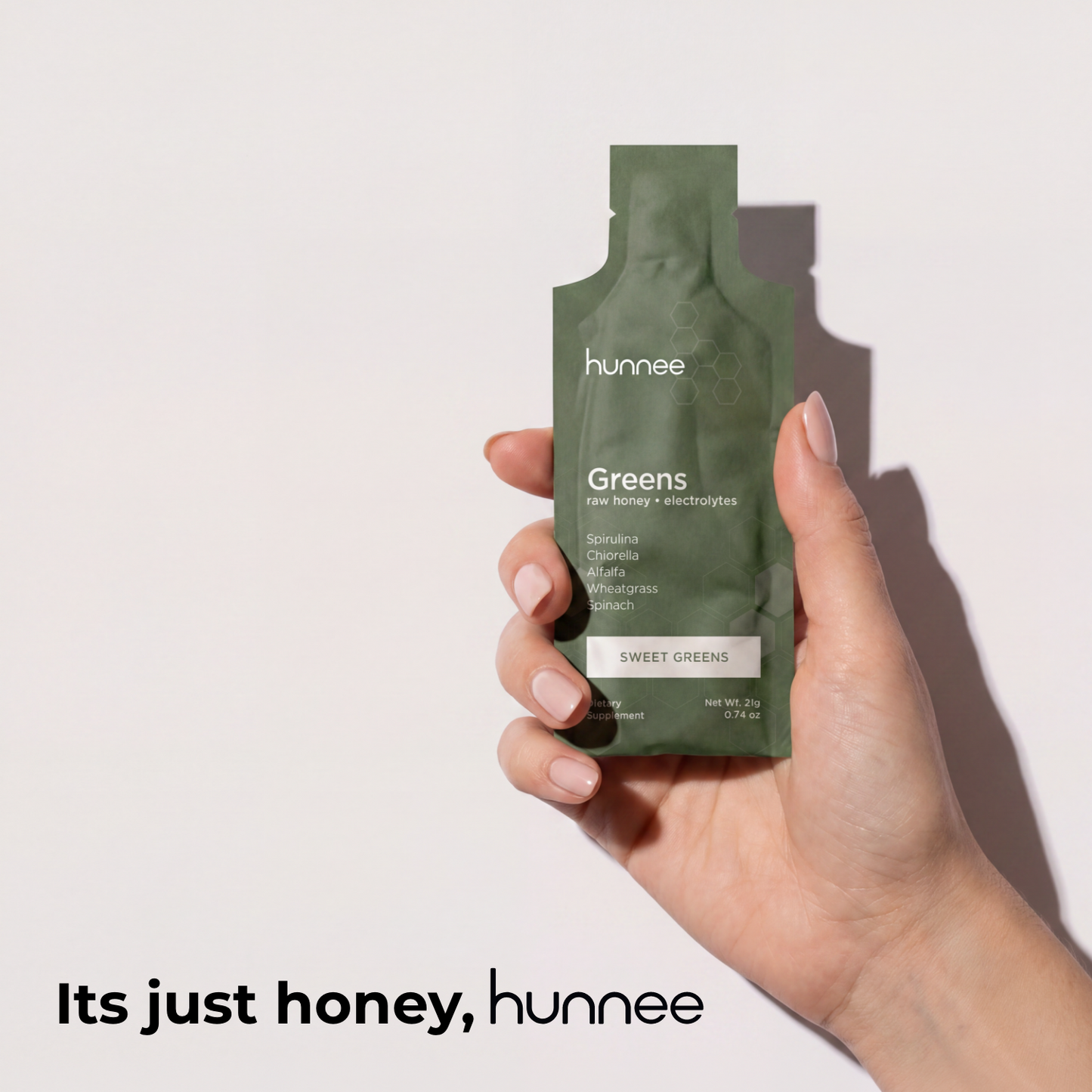 Hand holding a green 'hunnee' package against a white background
