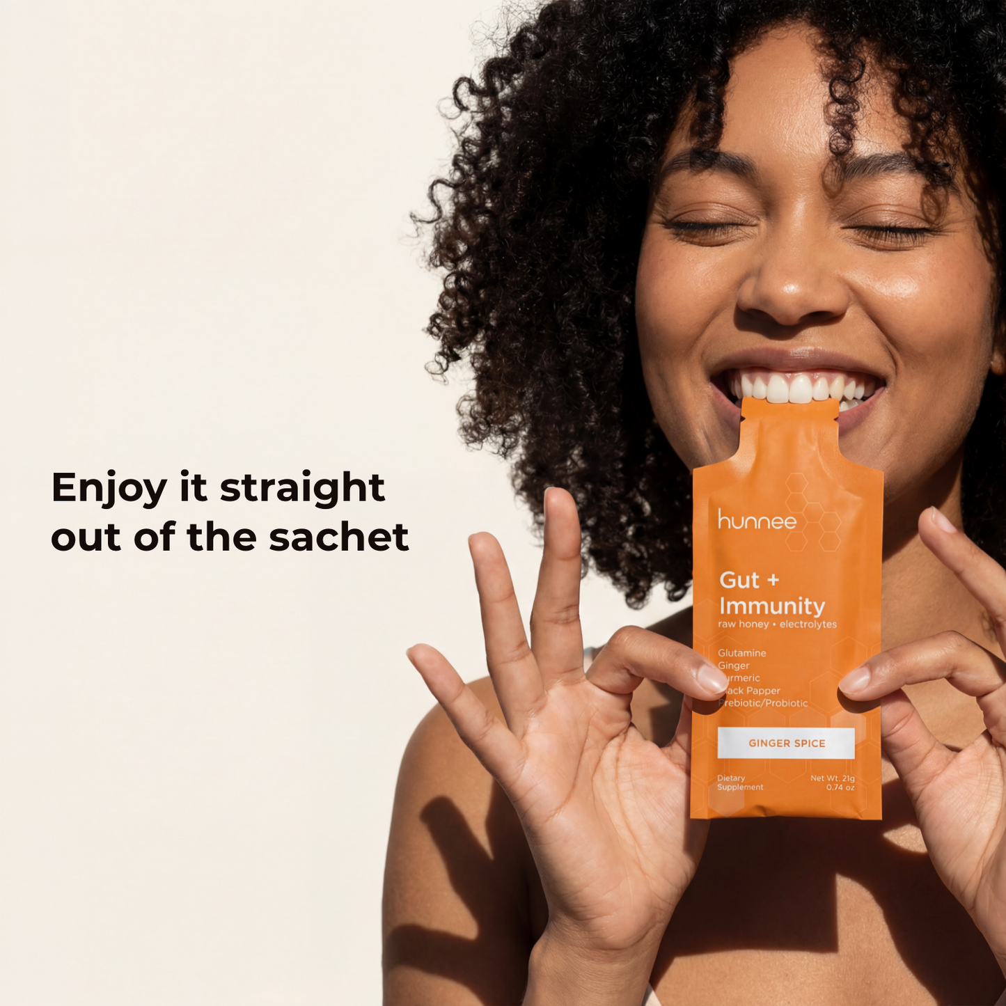 Woman holding a Hunnee Gut + Immunity supplement packet with text on a beige background