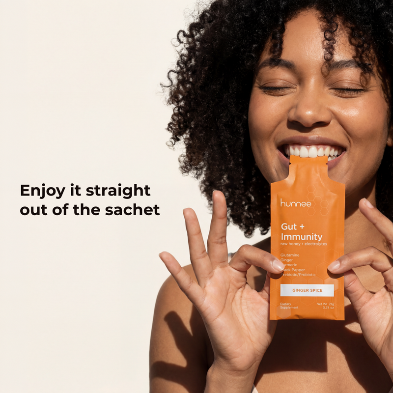 Woman holding a Hunnee Gut + Immunity supplement packet with text on a beige background
