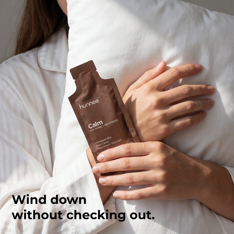 Person holding a brown packet labeled 'hunee Calm' against a white pillow.