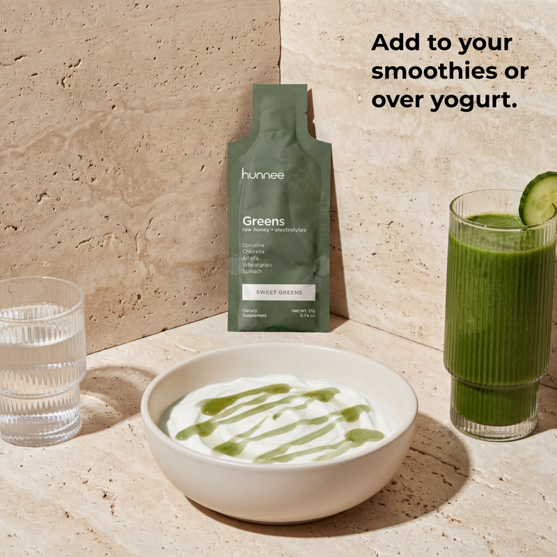 Hunnee Greens package with a glass of green juice and a bowl of yogurt on a stone surface.